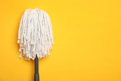 Photo of String mop on yellow background. Space for text