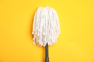 Photo of String mop on yellow background, top view