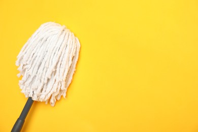 Photo of String mop on yellow background, top view. Space for text