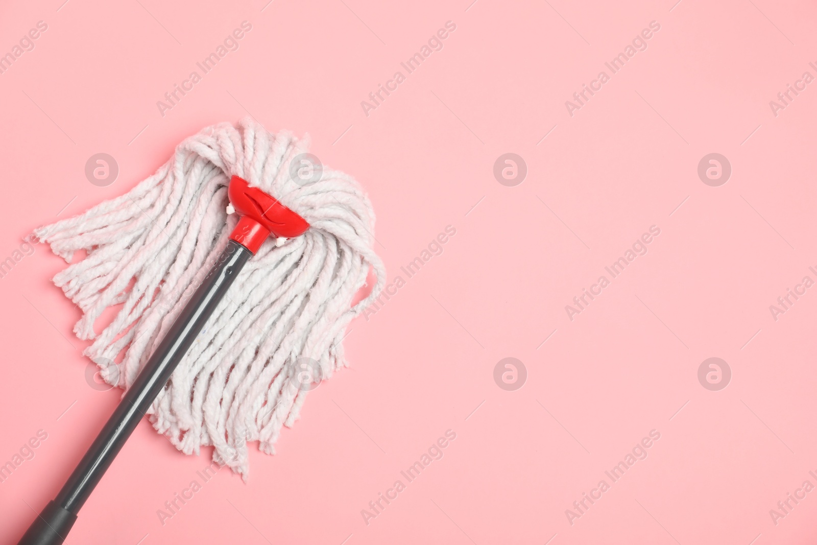 Photo of String mop on pink background, top view. Space for text