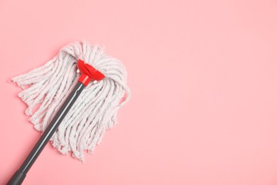 Photo of String mop on pink background, top view. Space for text