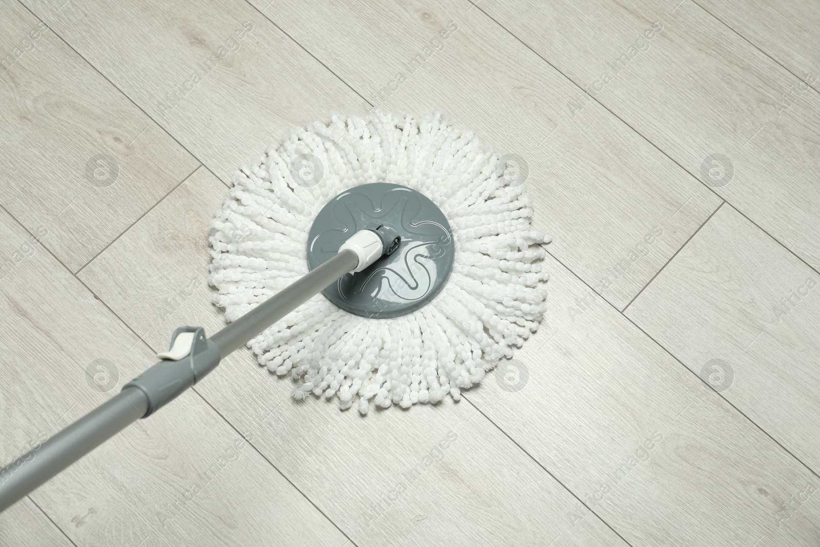 Photo of String mop on wooden floor. Cleaning equipment