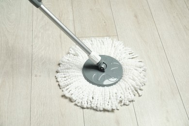 Photo of String mop on wooden floor. Cleaning equipment