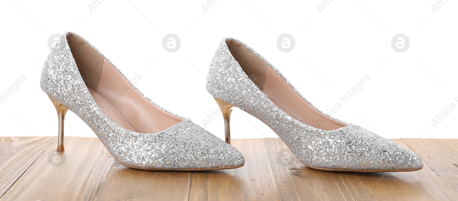 Photo of Beautiful high heeled shoes on wooden table against white background