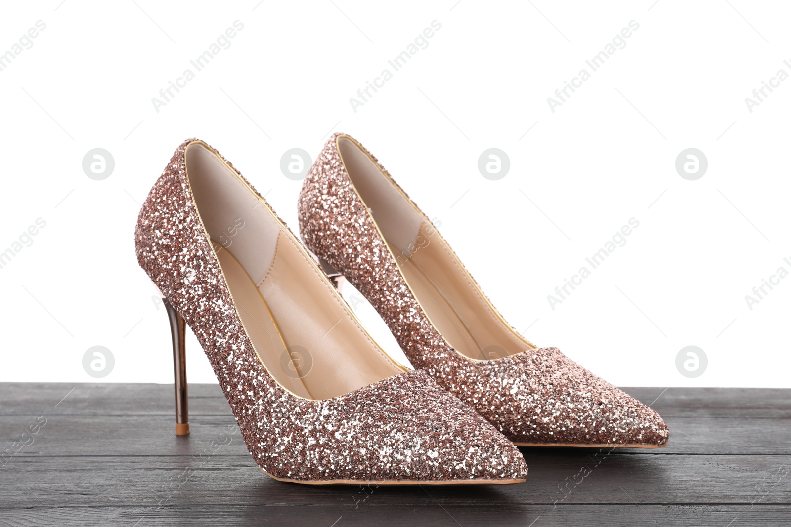 Photo of Beautiful high heeled shoes on black wooden table against white background