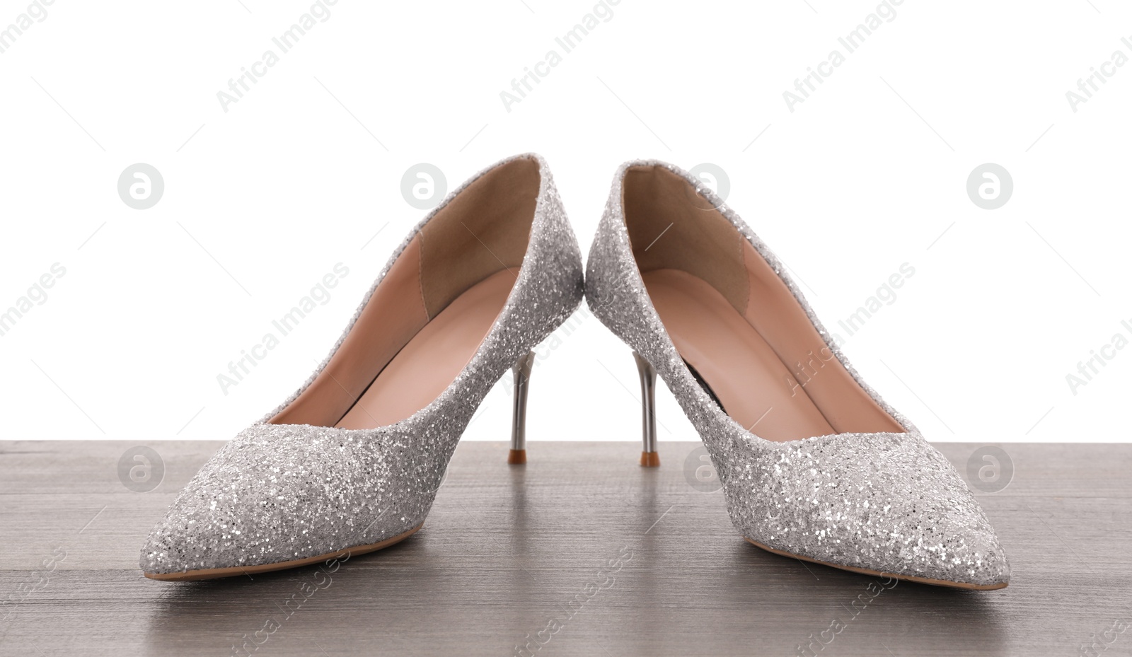 Photo of Beautiful high heeled shoes on wooden table against white background