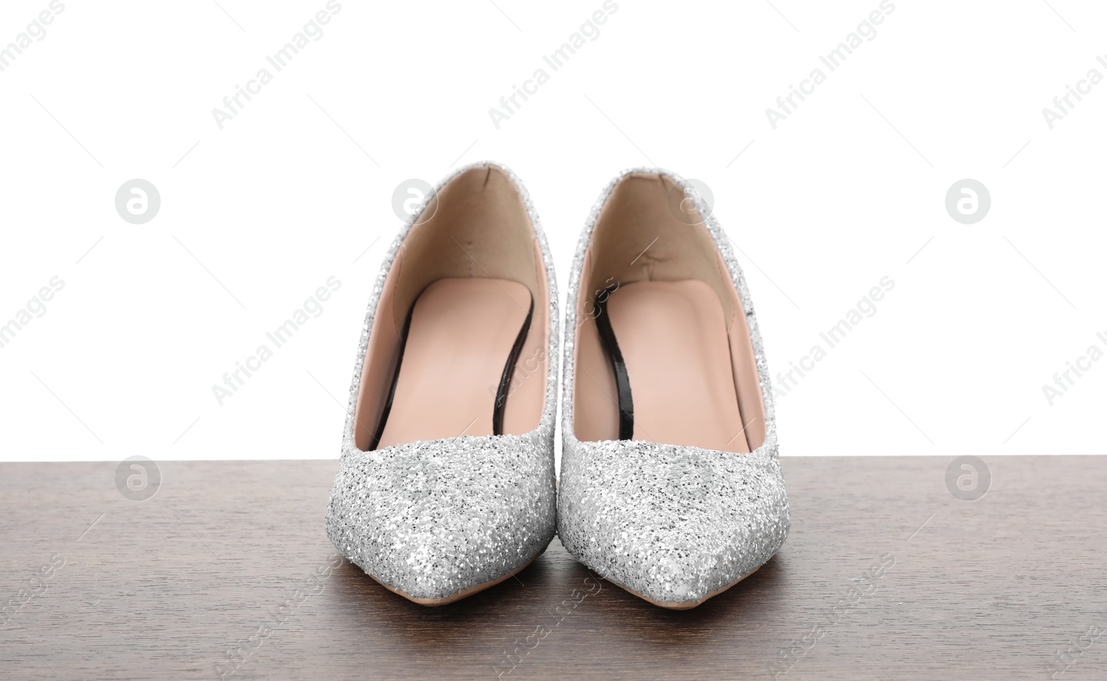 Photo of Beautiful high heeled shoes on wooden table against white background