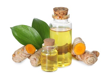 Photo of Bottles of turmeric essential oil, raw roots and leaves isolated on white