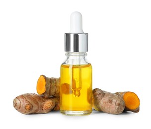 Photo of Bottle of turmeric essential oil and raw roots isolated on white