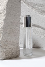 Photo of Bottle of serum and concrete block on light background