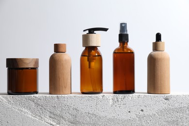 Different cosmetic products on concrete surface against white background