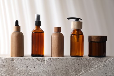 Photo of Different cosmetic products on concrete surface against light background