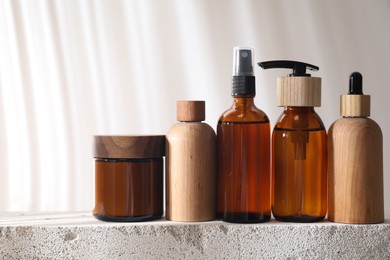 Photo of Different cosmetic products on concrete surface against light background