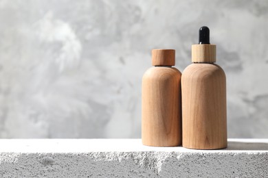 Bottles of cosmetic products on concrete surface against gray background, space for text