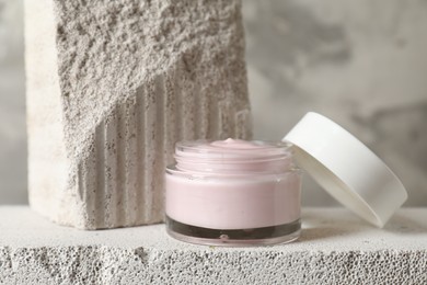 Photo of Jar of cream and lid on concrete block