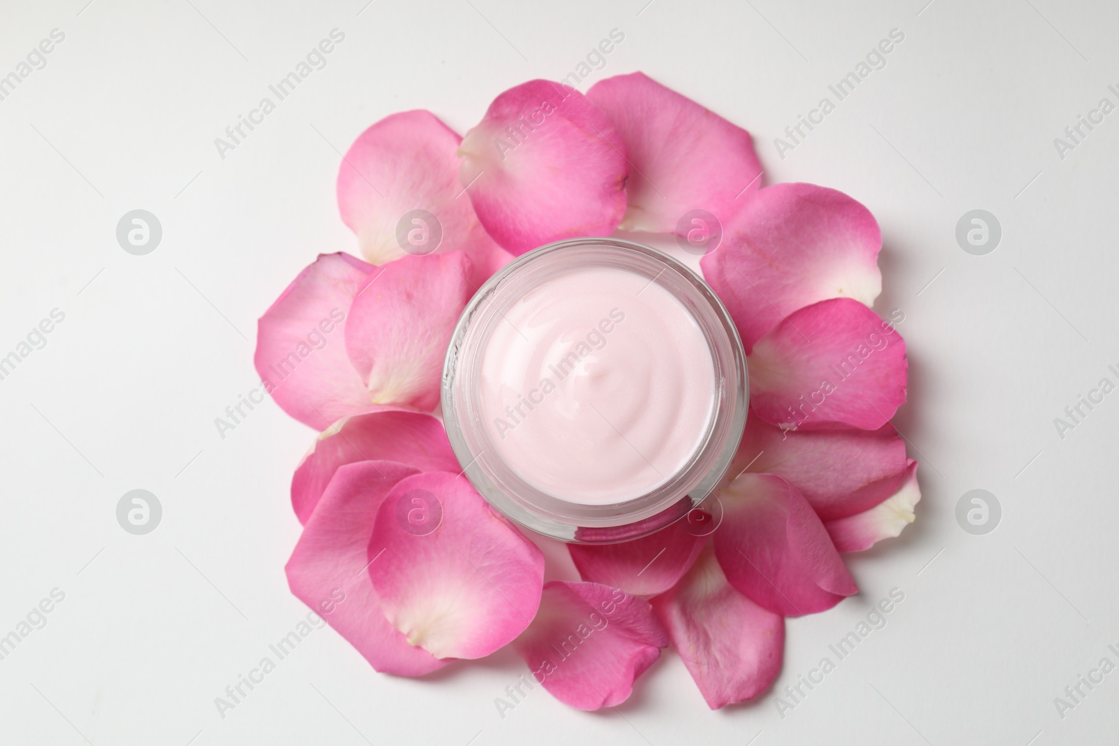 Photo of Jar of cream and pink petals on white background, top view