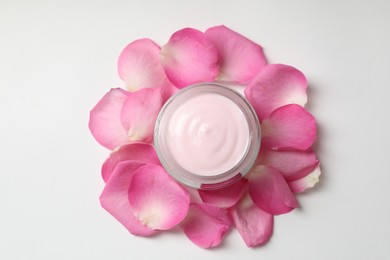 Photo of Jar of cream and pink petals on white background, top view