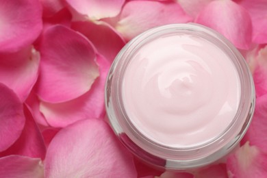 Jar of cream on pink petals, top view