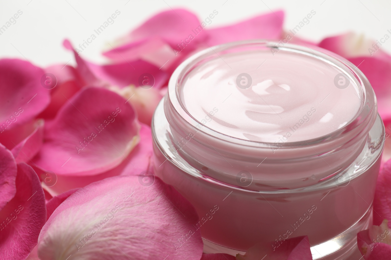 Photo of Jar of cream and pink petals on table, closeup