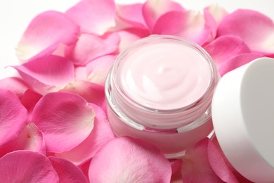 Photo of Jar of cream and pink petals on table, closeup