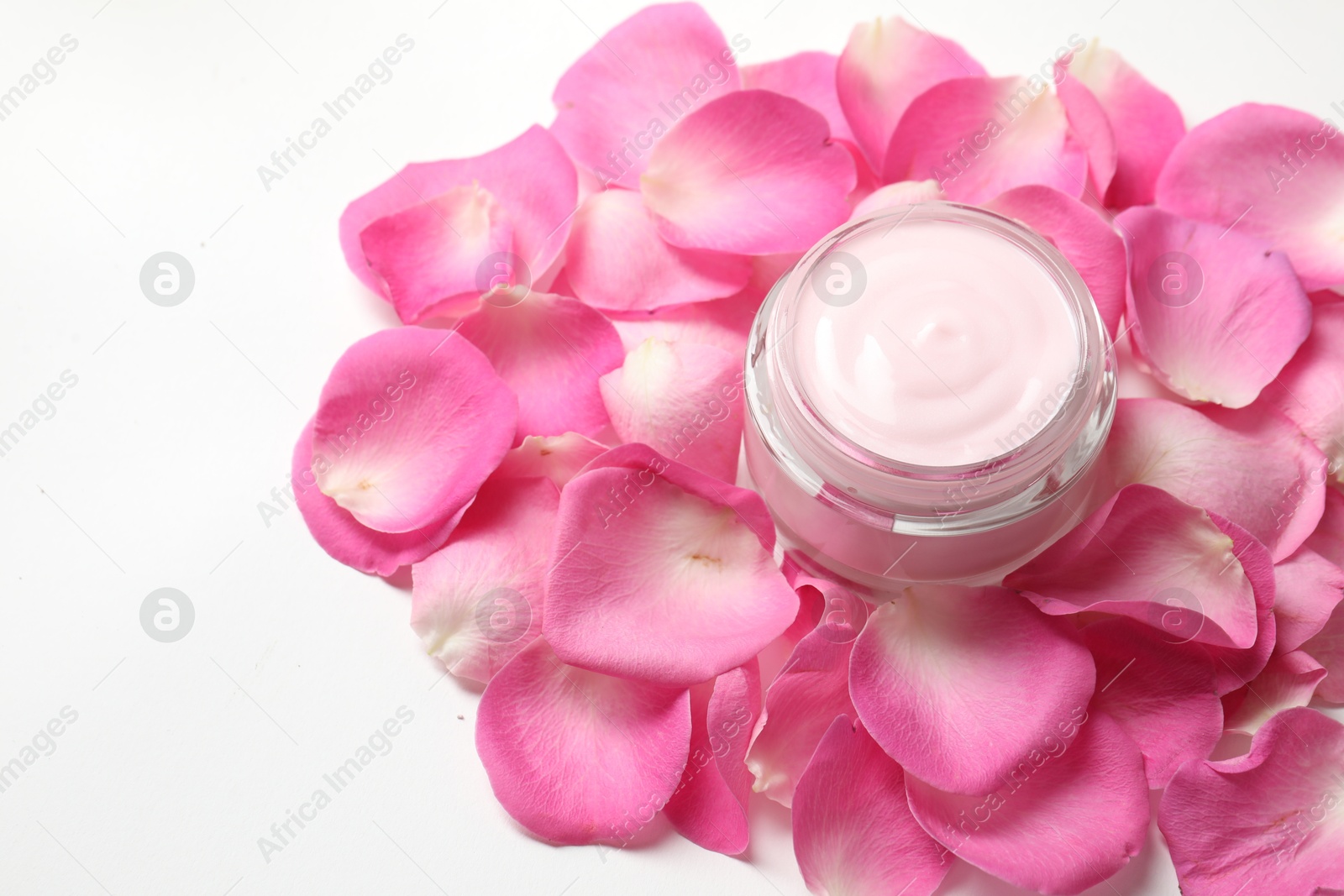 Photo of Jar of cream and pink petals on white background, above view. Space for text