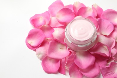 Jar of cream and pink petals on white background, above view. Space for text