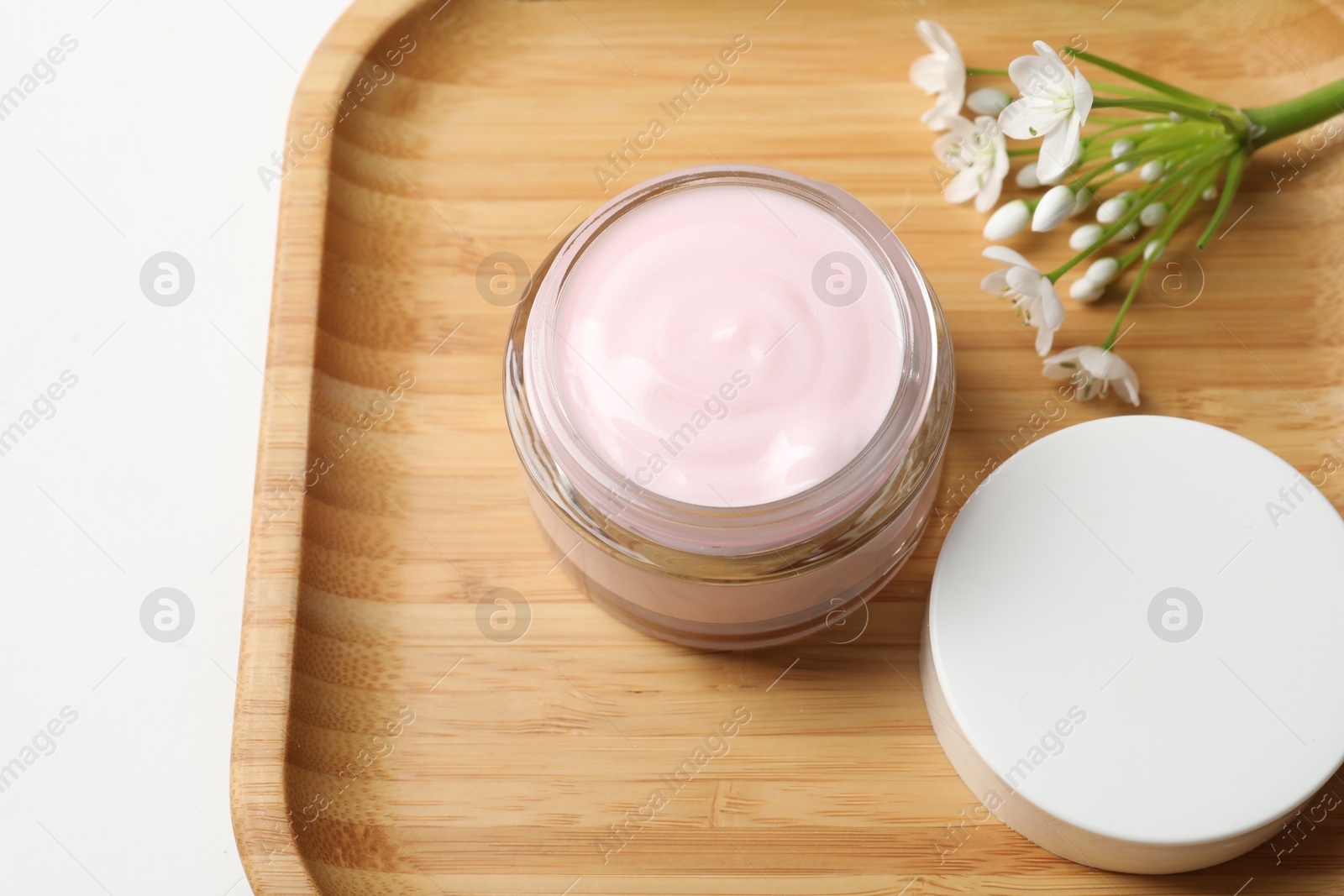 Photo of Jar of cream and beautiful flowers on white table, above view