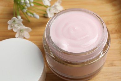 Photo of Jar of cream and beautiful white flowers on table, closeup