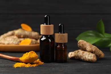 Photo of Turmeric oil, powder, roots and green leaves on dark wooden table