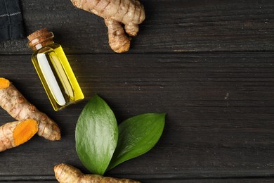 Photo of Turmeric oil, roots and green leaves on dark wooden table, flat lay. Space for text