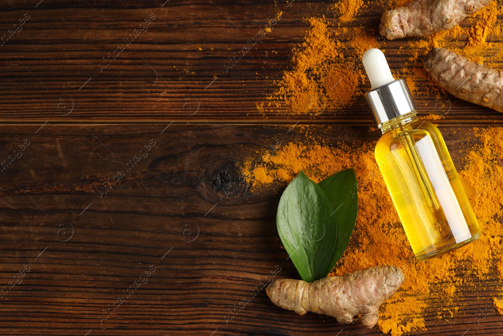 Photo of Turmeric oil, roots and green leaves on wooden table, flat lay. Space for text