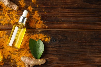 Photo of Turmeric oil, roots and green leaves on wooden table, flat lay. Space for text