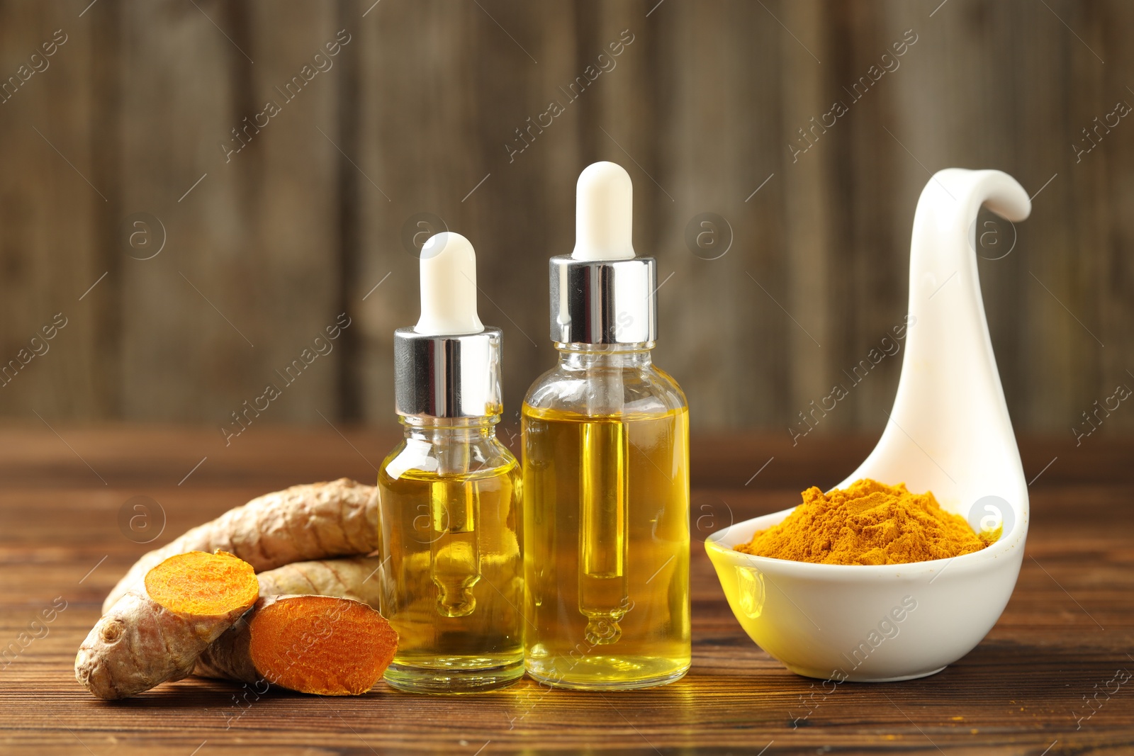 Photo of Turmeric oil, roots and powder on wooden table