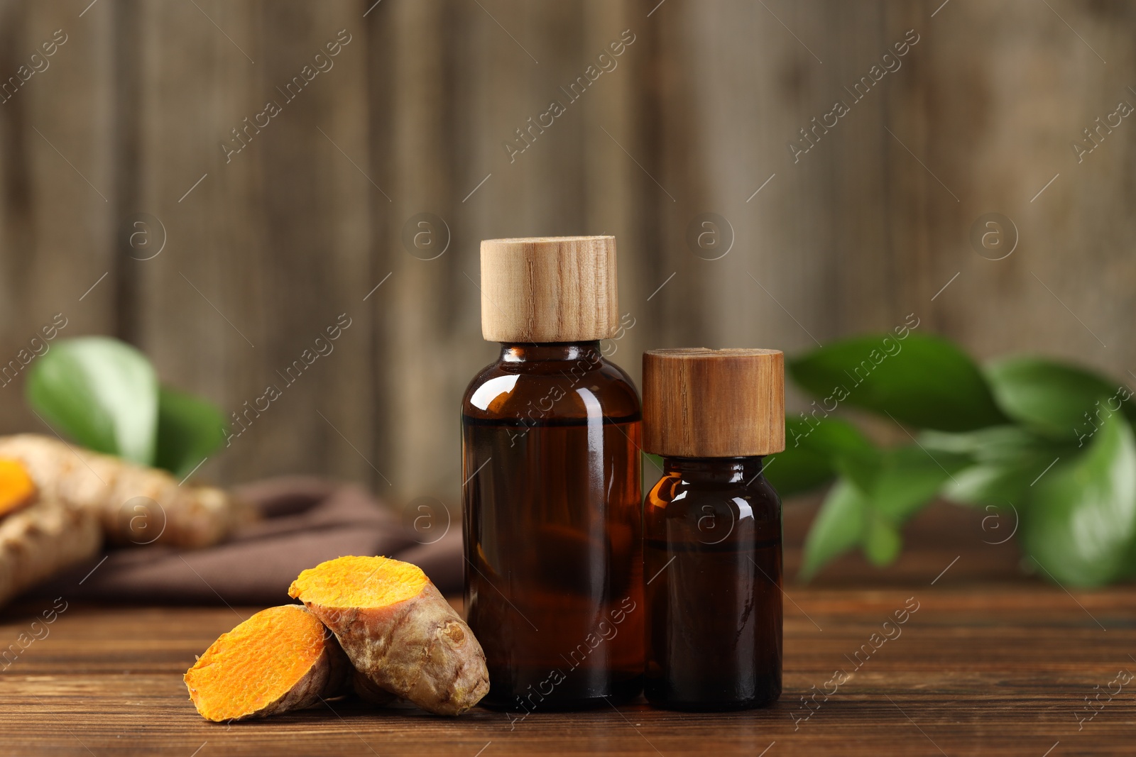 Photo of Turmeric oil and roots on wooden table