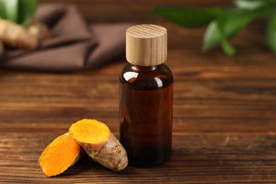 Photo of Turmeric oil and roots on wooden table, closeup