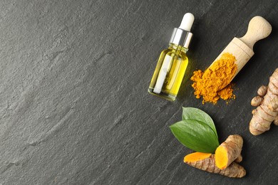 Photo of Turmeric oil, powder, roots and green leaves on black table, flat lay. Space for text