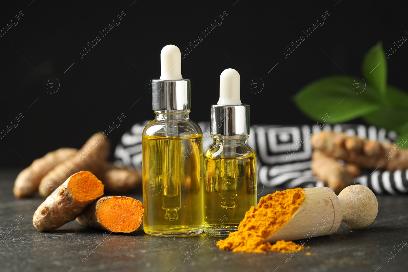 Photo of Turmeric oil, powder and roots on black table