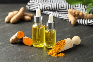 Photo of Turmeric oil, powder and roots on black table