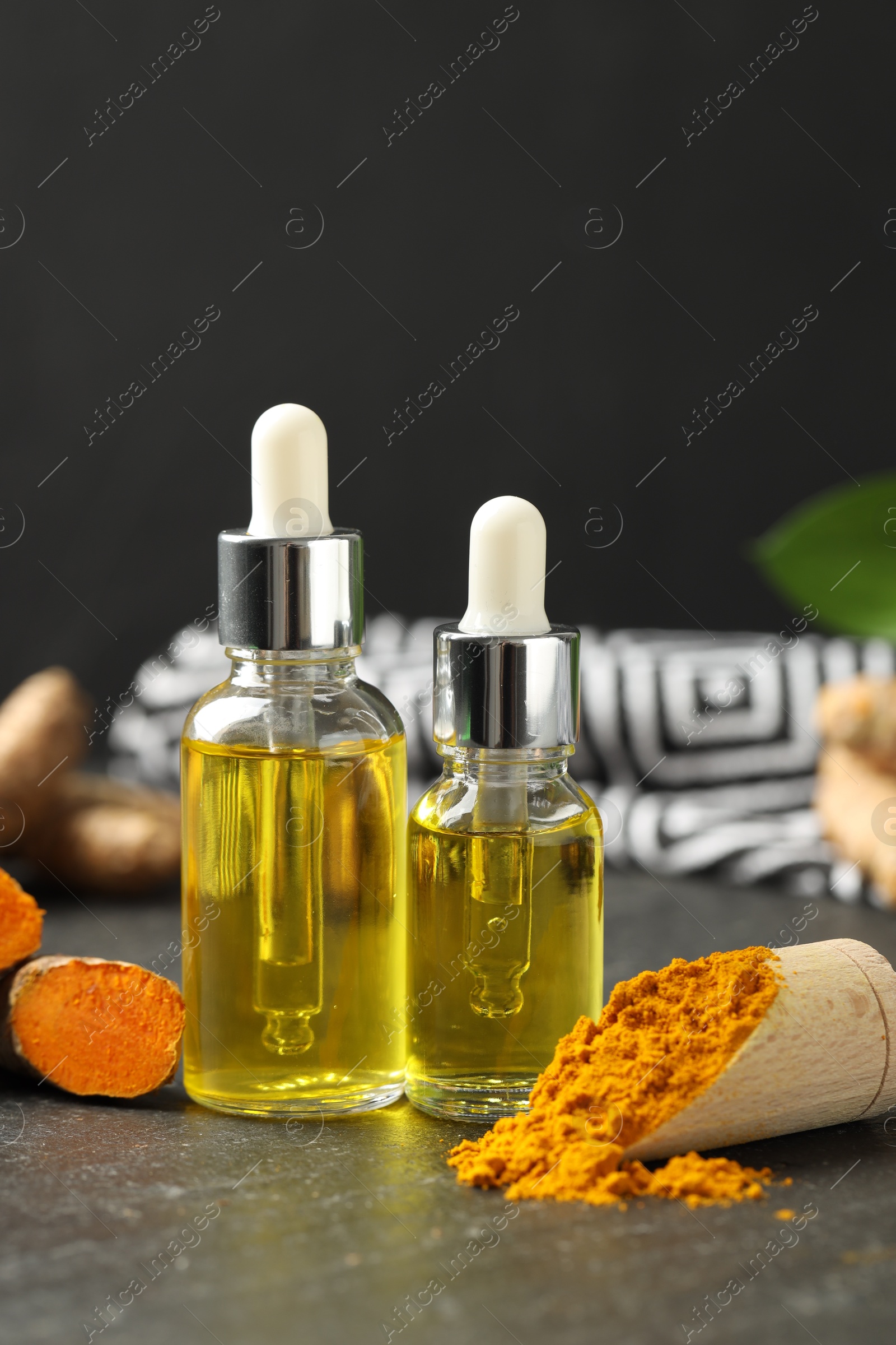 Photo of Turmeric oil, powder and root on black table, closeup