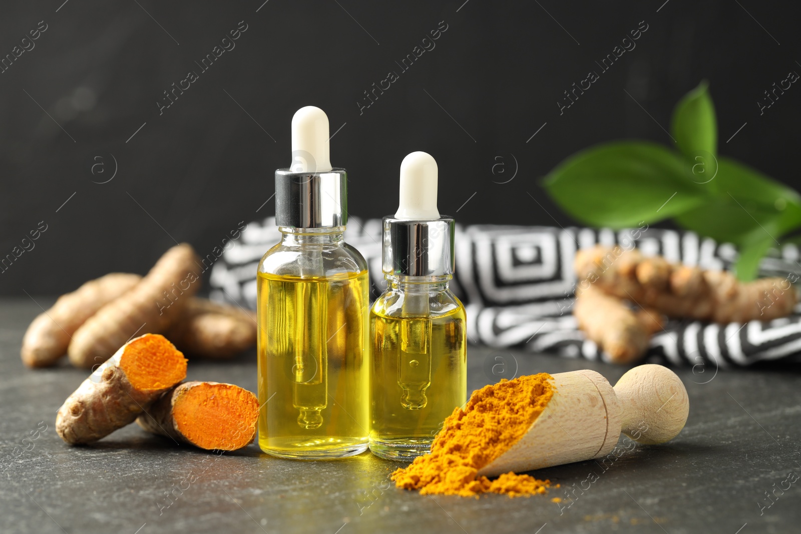 Photo of Turmeric oil, powder and roots on black table