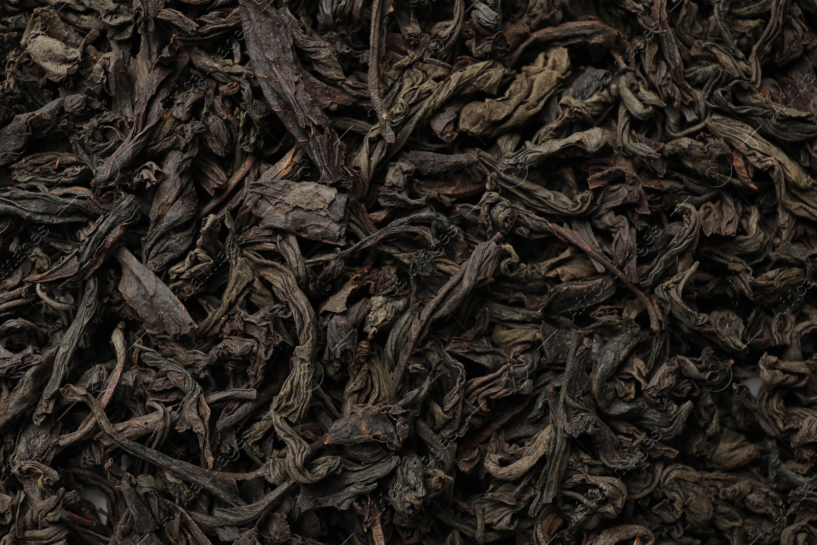 Photo of Pile of dry tea leaves as background, top view