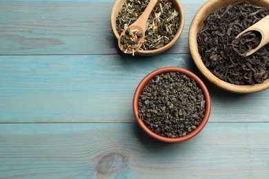 Photo of Different dry tea leaves in bowls on light blue wooden table, flat lay. Space for text