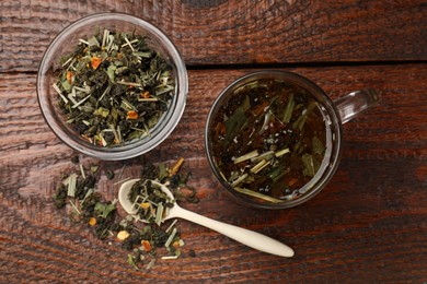 Photo of Aromatic tea in glass cup and dry leaves on wooden table, flat lay