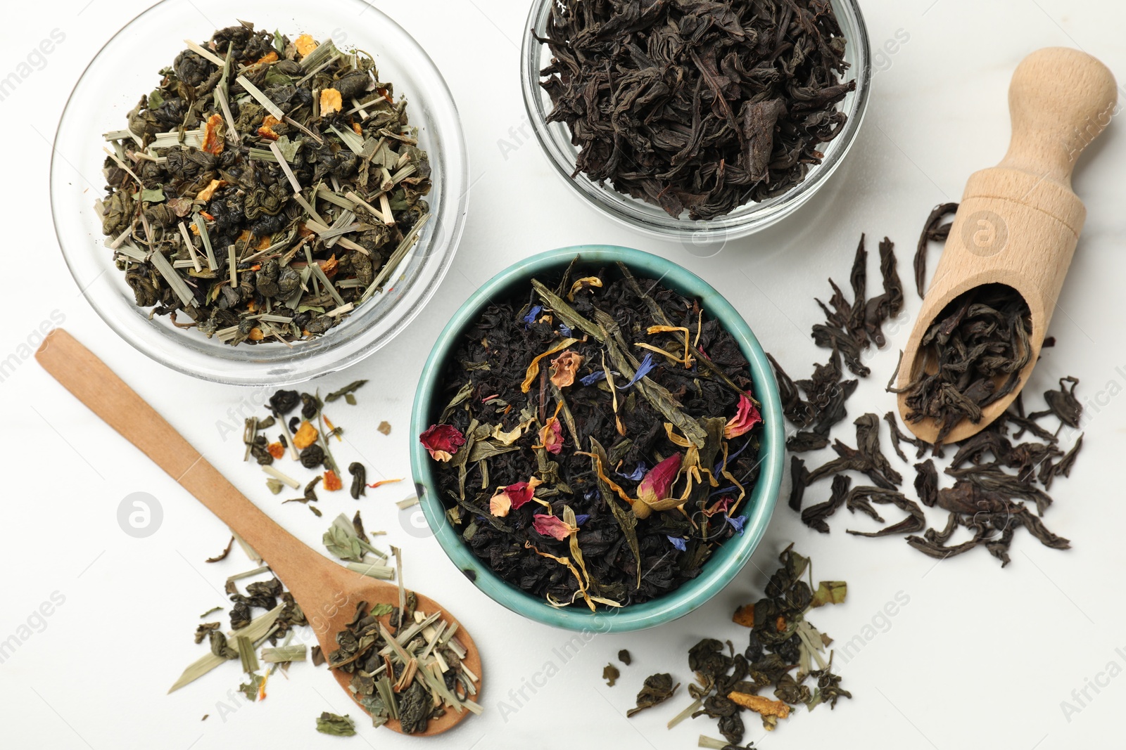 Photo of Different dry tea leaves on white table, flat lay