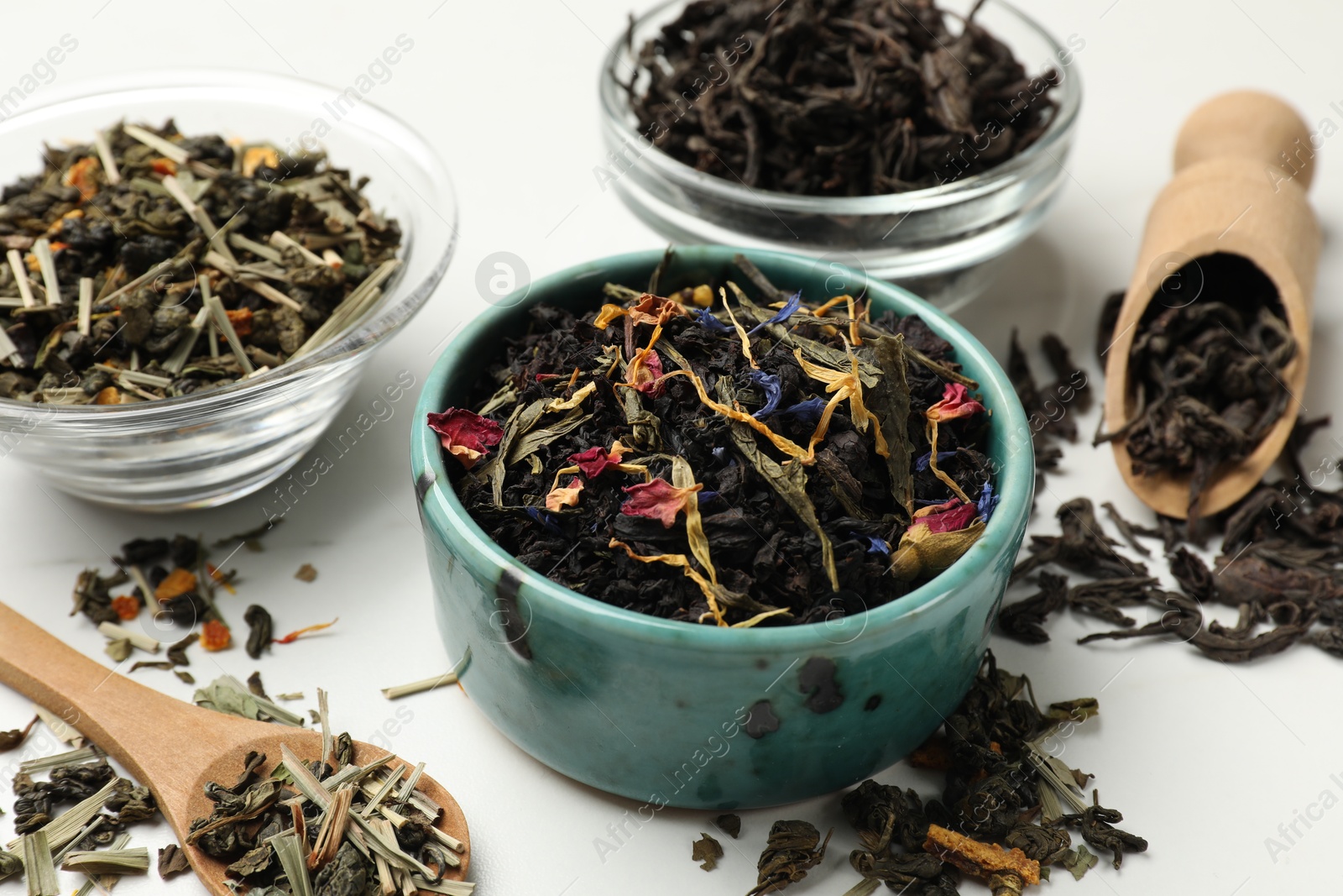 Photo of Different dry tea leaves on white table, closeup