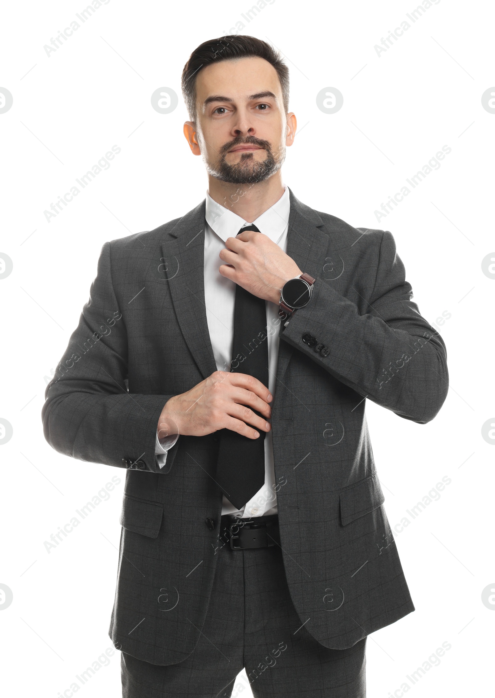 Photo of Confident man in classic suit straightening tie on white background