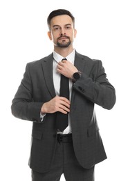 Photo of Confident man in classic suit straightening tie on white background