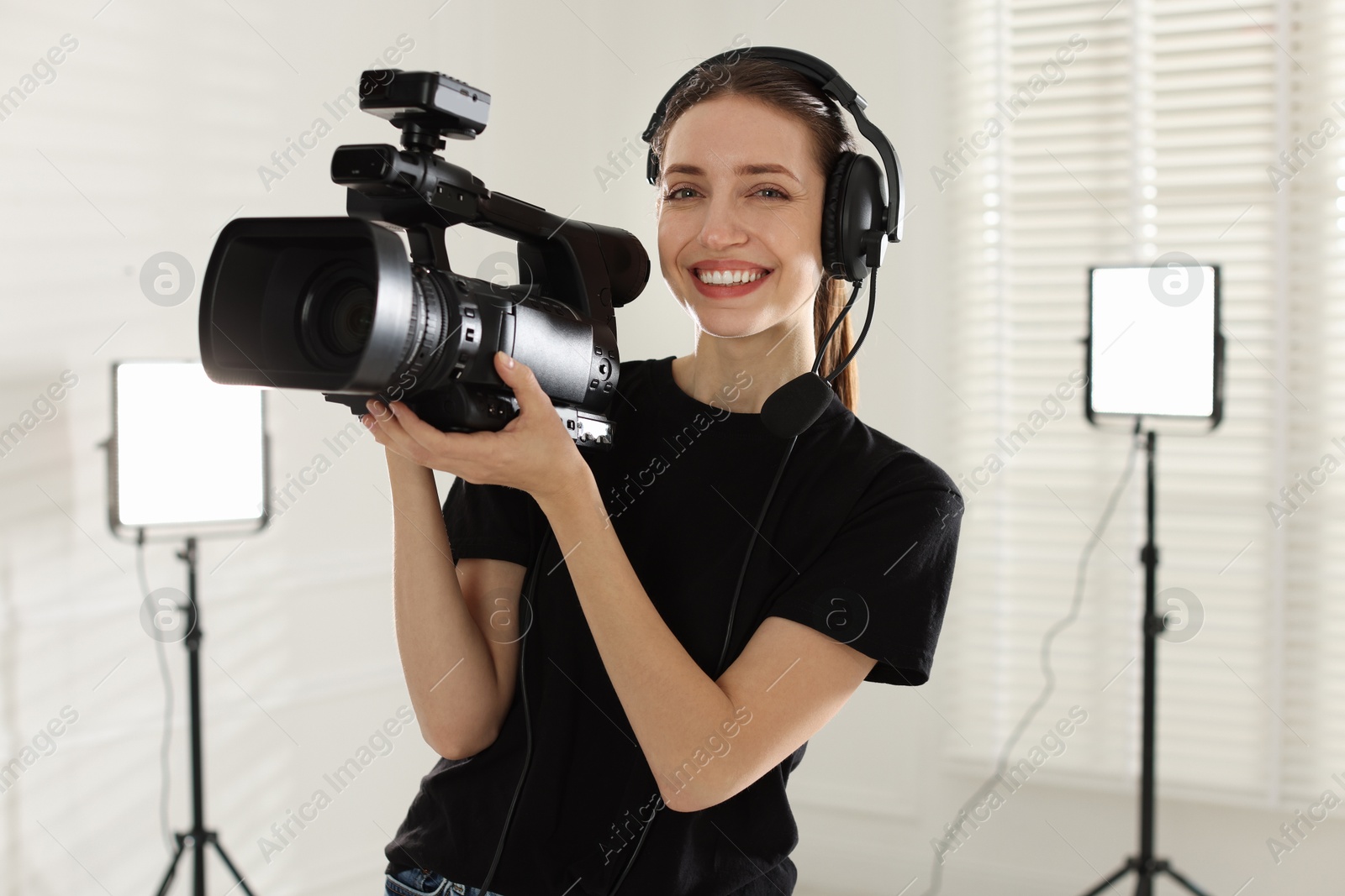 Photo of Happy woman with professional video camera and headset in studio