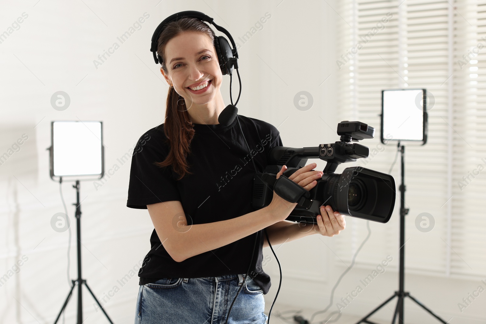 Photo of Happy woman with professional video camera and headset in studio