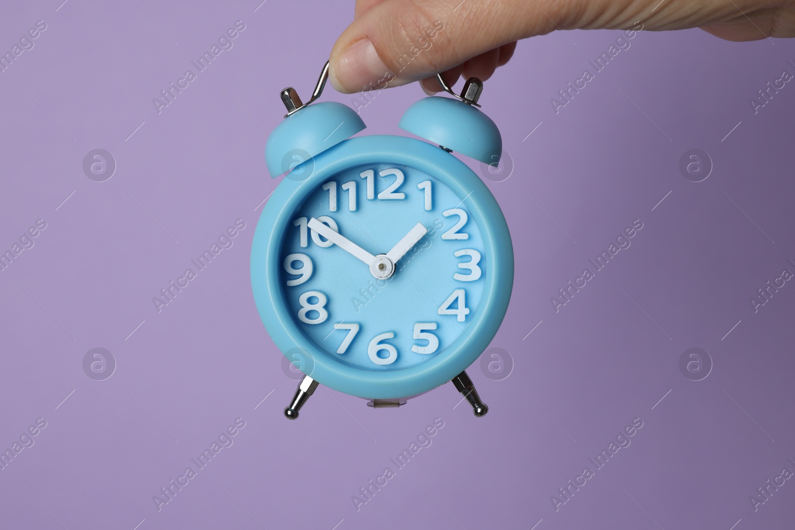 Photo of Woman with alarm clock on lilac background, closeup